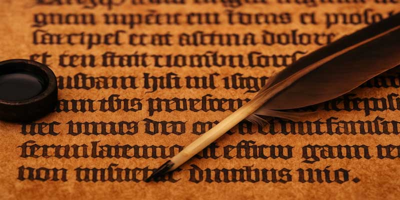 Quill pen writing with dark brown ink on medieval manuscript parchment